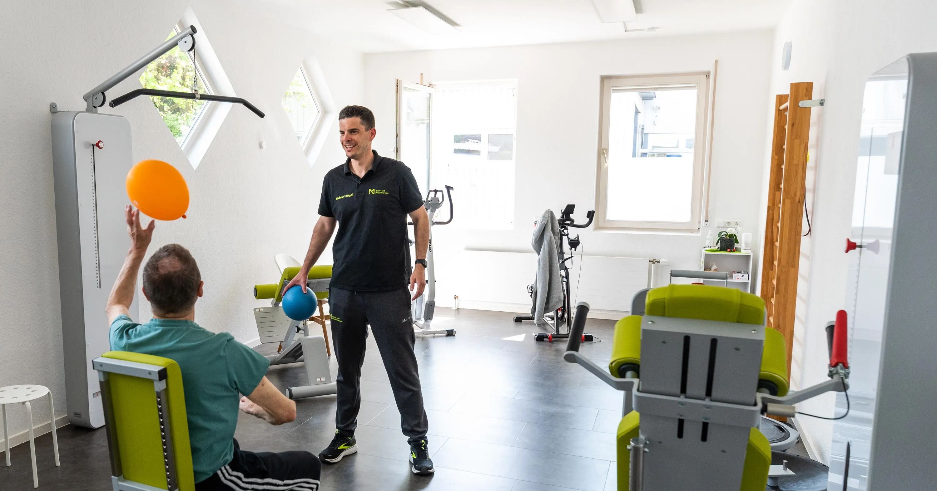 Trainingsraum der Praxis, Therapeut und Patient mit Gymnastikball