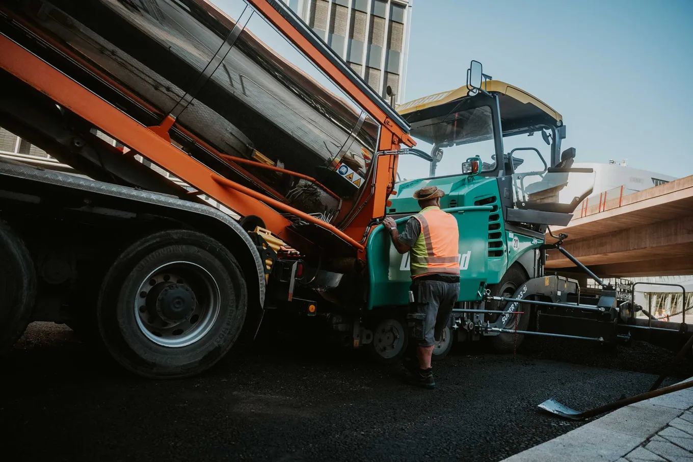 Asphaltfertiger und Kipper im Einbau auf einer Baustelle