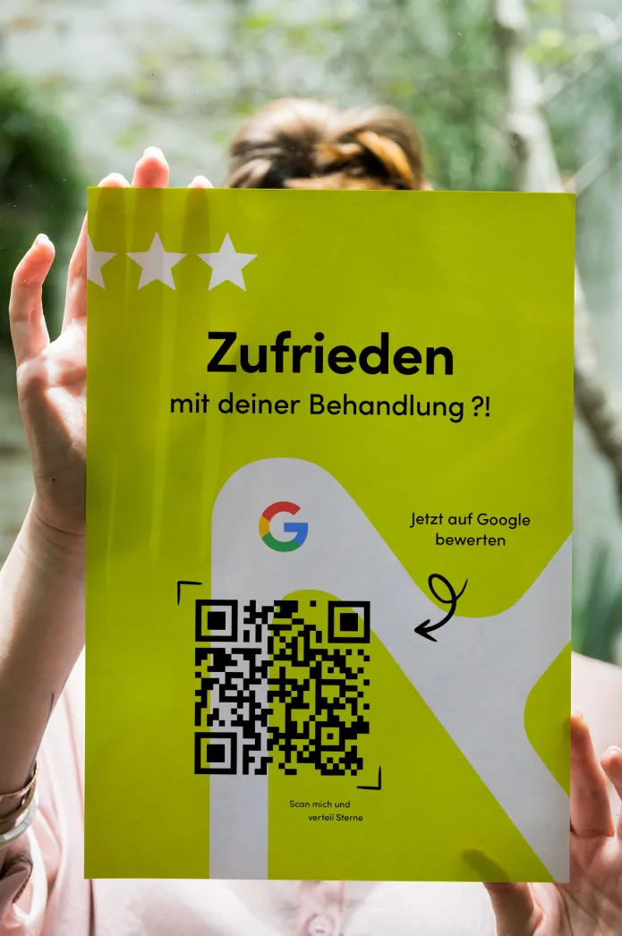 Person hält einen limettengrünen Flyer zur Google-Bewertung hoch