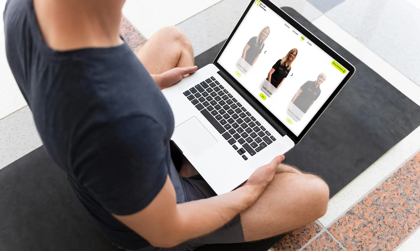 Person am Boden mit Laptop, darauf die Übungsseite der Website
