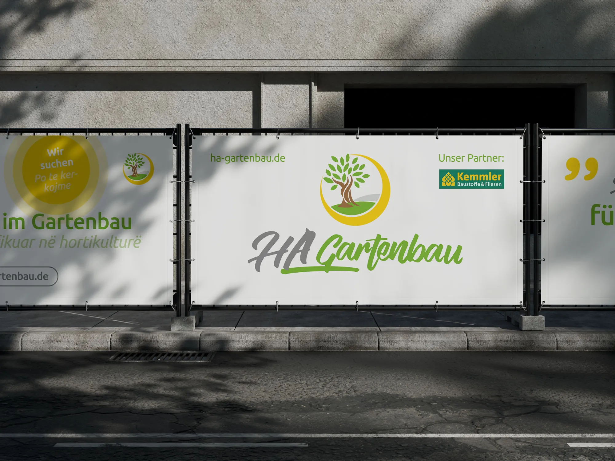 Banner von HA Gartenbau an einem Bauzaun, mit Logo, Website-Adresse und dem Partner Kemmler Baustoffe