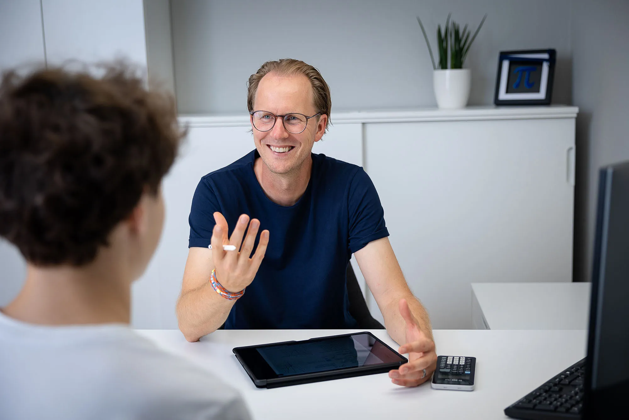 Tillmann Brandt erklärt einem Schüler am Schreibtisch etwas, vor ihm ein Tablet